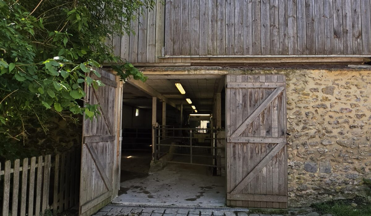 Anciennes étables de la Ferme de la Noue avec une façade en pierre et en bois.